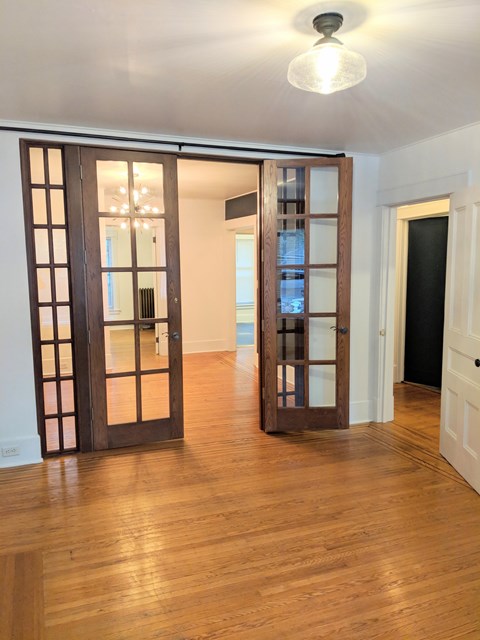 A room with a wooden floor and a white ceiling with a light fixture.